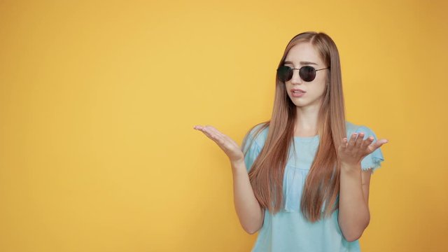 girl brunette in blue t-shirt over isolated orange background shows emotions