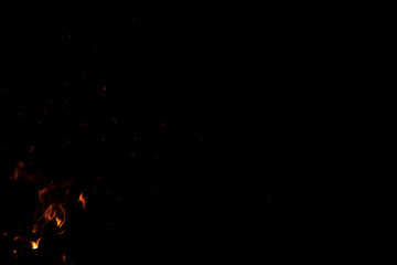 tongues of flame in motion with sparkles in simple black background empty space for copy or text