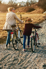 Mother and daughter with bicycles on countryside.