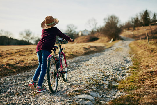 Cute little ten year old girl riding bicycle on countryside.