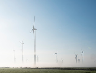 wind turbines in green meadow near aurich in ostfriesland on misty morning in august