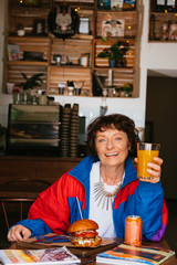 Portrait of a happy beautiful fashionable grandmother sitting in a cafe in stylish bright clothes