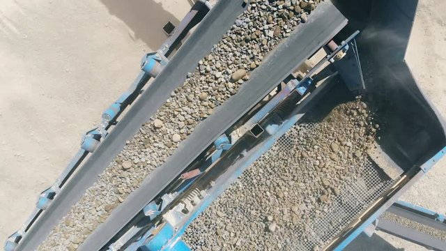 Stones moving on a line at a quarry. Heavy industry mining equipment.