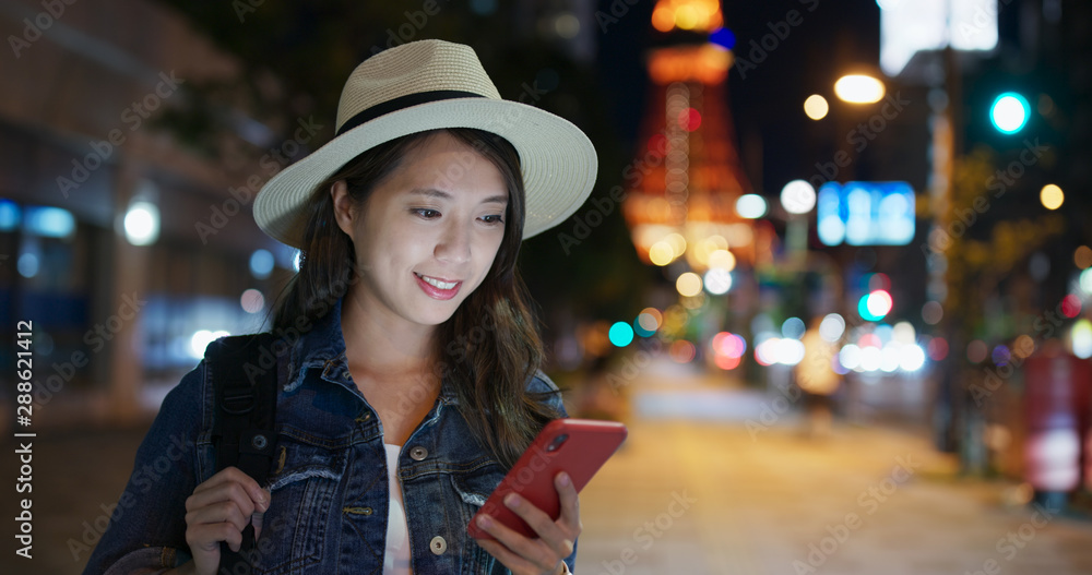 Wall mural woman use of mobile phone in city at night