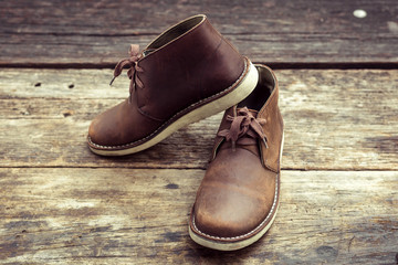 Brown stylish boots on wood background,  retro color