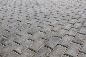 Low angle closeup of old pedestrian pavement surface paved with gray stone bricks