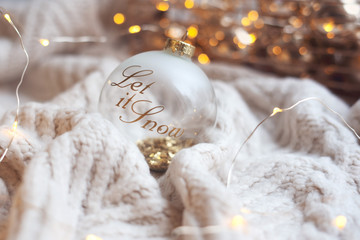 Christmas glass ball on knitted plaid and christmas lights