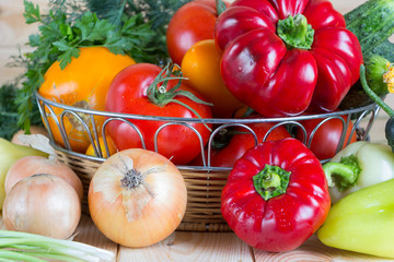 Close up fresh harvested vegetables in wicker basket on wooden table. Natural homegrown products.