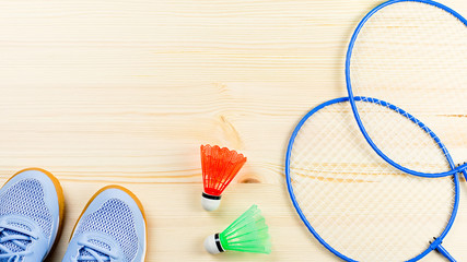 Colorful shuttlecocks and badminton rackets flat lay on wooden desk. Sports and recreation concept