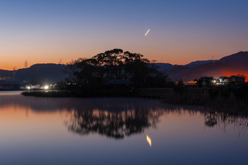早朝の湖に映り込む朝焼けと星