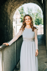 Outdoor portrait of beautiful woman with curly hair, wearing blue dress