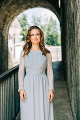 Fototapeta premium Outdoor portrait of beautiful woman with curly hair, wearing blue dress
