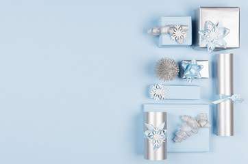 Christmas background for your design and text - soft pastel blue and silver gift boxes with bows, christmas tree on blue backdrop, top view, copy space.