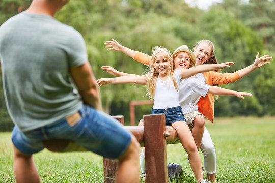 Kinder und Eltern balancieren auf Schaukel