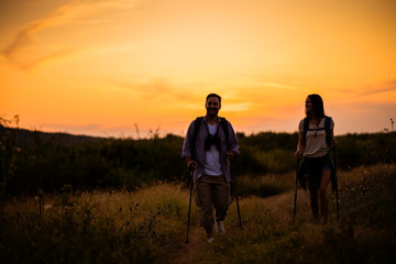 Fototapeta na wymiar Happy couple is hiking in mountain in sunset.