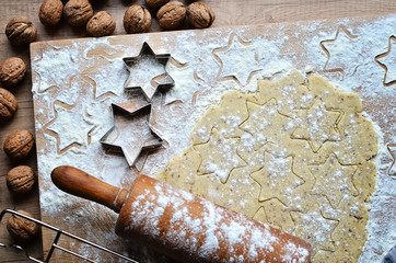 Baking handmade christmas cookies in star shape with flour and rolling pin on the wooden board 