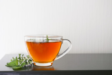 cup of hot herbal tea with mint, lemon balm and oregano flowers