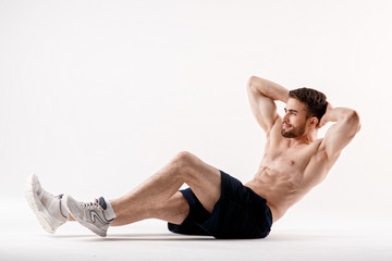young man with a beard of a sports physique does an exercise on the muscles of the abdominal cavity...
