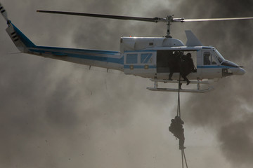 Deploying troops from a military helicopter using fast-roping technique. Special force landing
