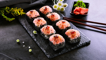 Baked roll with shrimp and masago caviar cap. Traditional sushi restaurant dish, menu item. National japanese cuisine appetizer. Delicious oriental snack, gourmet seafood on wooden platter closeup