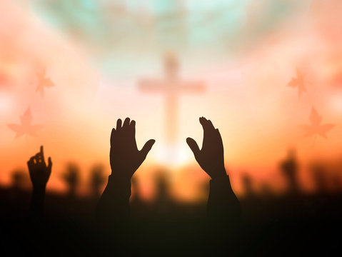 Worship God concept: human rising hands over blurred cross background