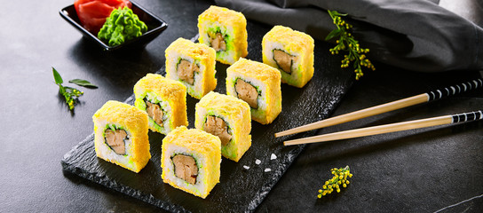 Tempura roll traditional Japanese dish. Sushi with raw salmon, eel and cucumber. Asian food and chopsticks on black plate. Japan restaurant meal concept. Modern gourmet food, delicious dinner