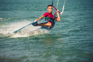 Professional kiter makes the difficult trick on a beautiful background. Kitesurfing Kiteboarding action photos man among waves quickly goes