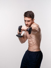 Fototapeta na wymiar Young athlete on a white background lifts dumbbells. training a bearded man athletic build