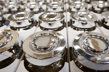 Several rows of containers with shiny metal lids on a production line in a factory or for sale in a store in packaging