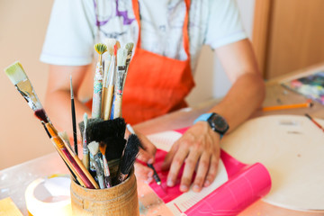Real work studio of the painter. Man is creating picture. Artist concept. Creative atmosphere. Paint brushes.