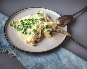 Homemade omelette Breakfast with green peas on ceramic round plate with fork and spoon, top view close-up