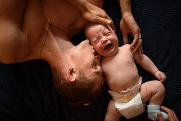 A young father lies next to his little son