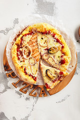 Hot seafood pizza with squid, mussels and fish fillet on wooden plate top view. Pizza ai frutti di mare topped with onion rings, red fish fillet, tomato sauce and mozzarella closeup