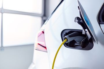 Close Up Of Power Cable Charging Environmentally Friendly Zero Emission Electric Car In Garage