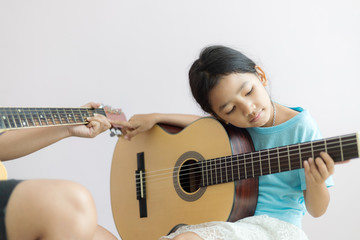 Mother teaching the daughter learning how to play acoustic classic guitar for jazz and easy listening song select focus shallow depth of field