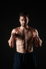 Fototapeta na wymiar sports man with a beard on a black background with gymnastic elastic bands in hands