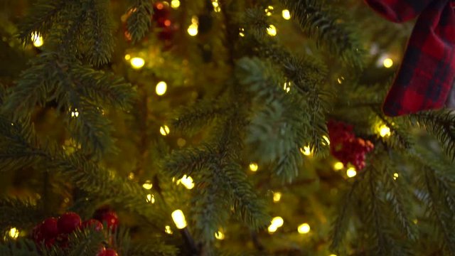 Closeup view of green Christmas tree glowing at night with golden led lights. Real time video footage.