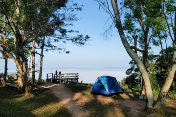 view morning of a camping tent and tourists relax on terrace view point around with sea of fog and blue sky background, itti view point, Khao Kho, Phetchabun, Thailand.