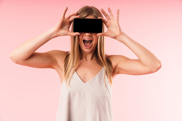 Image of beautiful young woman wearing dress laughing and holding smartphone at her face