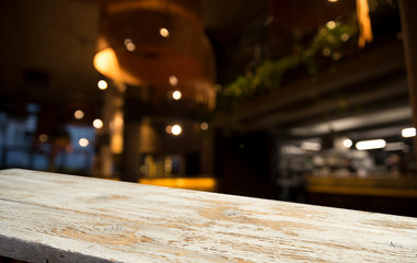 Empty wood table top on blur light gold bokeh of cafe restaurant in dark background