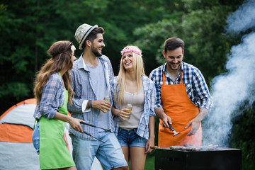 Group of happy friends having barbecue party in forest