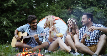 Happy friends playing music and enjoying bonfire