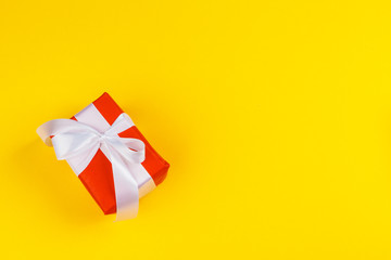 Decorated colored present on yellow background flatlay