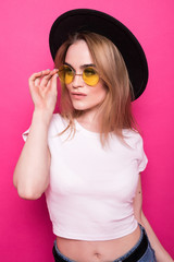 Portrait of an excited young girl in summer clothes looking at copy space over pink background