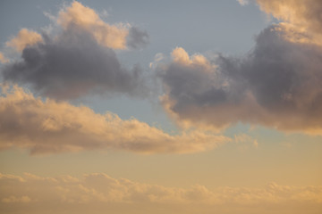Naklejka na ściany i meble Close up of clouds on a pastel blue and golden sky.