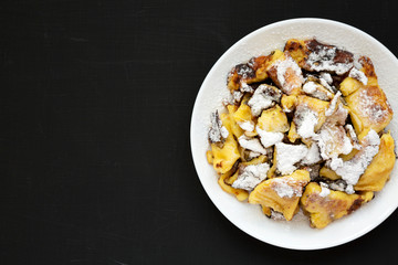 Homemade german Kaiserschmarrn pancake on a black background, top view. Flat lay, overhead, from above. Copy space.
