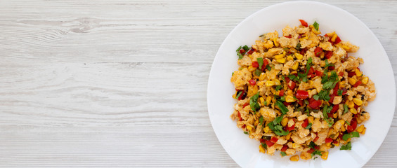 Homemade southwestern egg scramble on a white plate on a white wooden background, view . Flat lay, overhead, from above. Copy space.