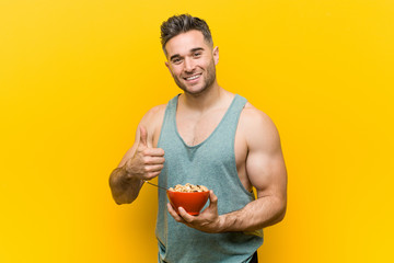 Caucasian man holding a cereal bowl smiling and raising thumb up