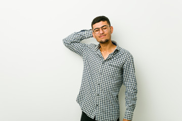 Young hispanic man touching back of head, thinking and making a choice.