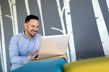 Smiling male blogger keyboarding article in electronic newspaper using laptop